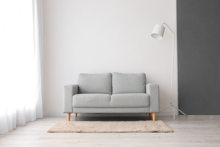 Stylish sofa and lamp near white wallの写真素材