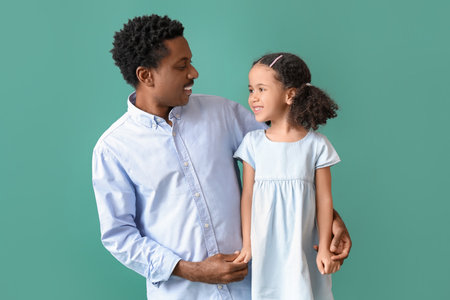 Portrait of little African-American girl and her father on green backgroundの写真素材