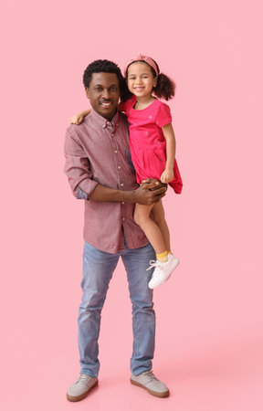 Portrait of little African-American girl and her father on pink backgroundの写真素材