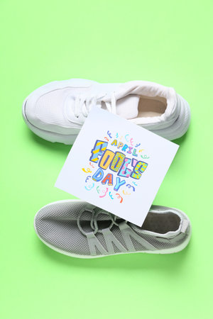 Shoes with tied laces and card with text APRIL FOOL'S DAY on green backgroundの写真素材