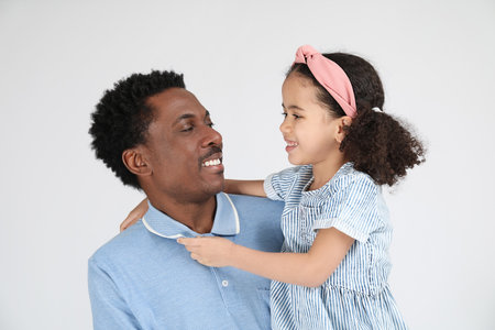 Portrait of little African-American girl and her father on gray backgroundの写真素材