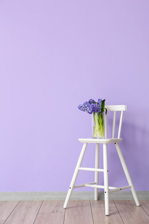 Vase with hyacinth flowers on chair near color wall in roomの写真素材