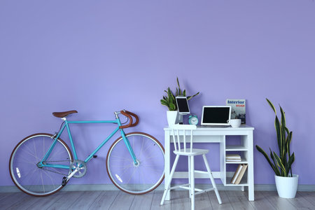 Comfortable workplace and bicycle near color wall in room interiorの写真素材