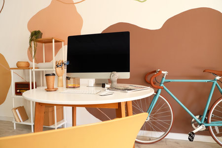 Workplace with modern computer and bicycle near color wallの写真素材