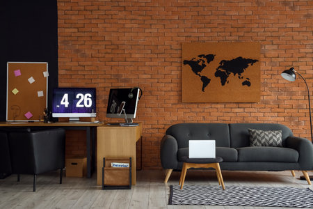 Interior of room with comfortable sofa and modern workplace near brick wall