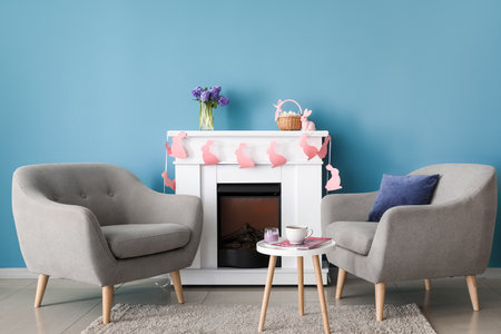 Comfortable armchairs near fireplace in room decorated for Easter celebrationの写真素材