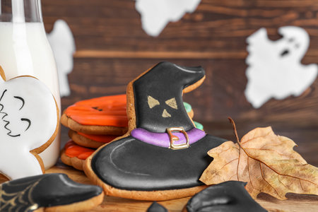 Board with Halloween cookies and fallen leaf on dark wooden background, closeupの写真素材