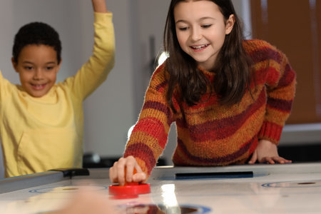 Little children playing air hockey indoors
