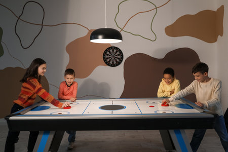 Little children playing air hockey indoors