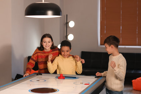Funny children playing air hockey indoors
