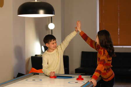 Little children playing air hockey indoors