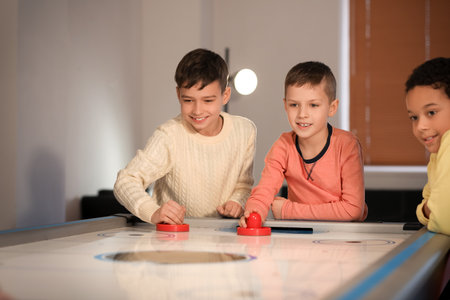 Funny children playing air hockey indoors