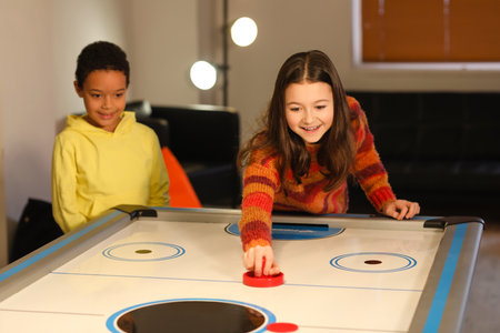 Little children playing air hockey indoors