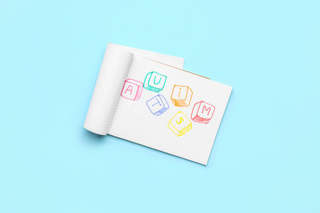 Notebook with word AUTISM on blue background