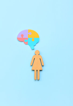 Wooden female figure with paper puzzle pieces on blue background. Concept of autistic disorderの写真素材