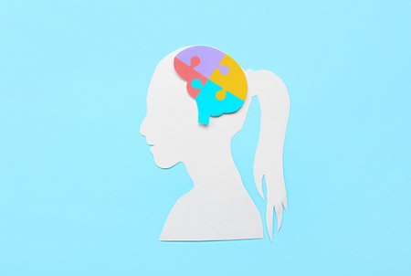 Paper female head with puzzle pieces on blue background
