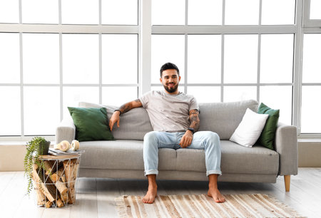 Handsome barefoot man sitting on sofa at homeの写真素材