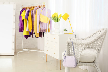 Interior of light dressing room with clothes, commode and armchairの写真素材