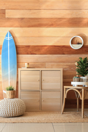 Interior of stylish room with wooden surfboard, commode and chairの写真素材