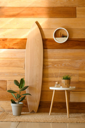Surfboard and table with houseplants near wooden wallの写真素材