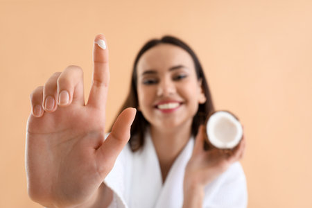 Young woman with coconut and oil on beige background, closeupの写真素材
