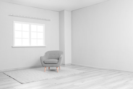 Gray armchair and carpet near light wall in big roomの写真素材