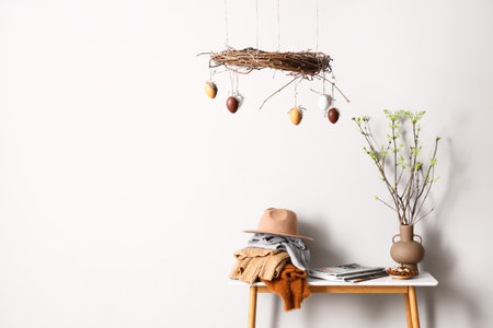 Different clothes, tree branches on table and stylish Easter decor near light wallの写真素材