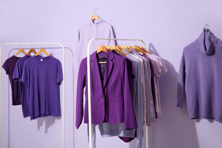 Racks with clothes in purple shades on lilac backgroundの写真素材