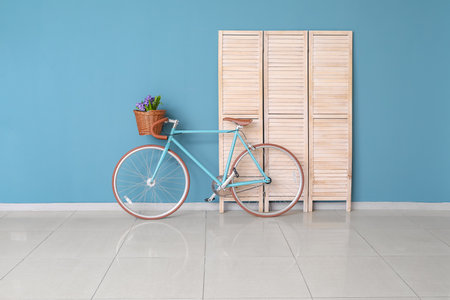 Modern bicycle and wooden folding screen near blue wall in empty roomの写真素材