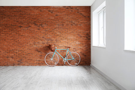 Modern bicycle near brick wall in empty roomの写真素材