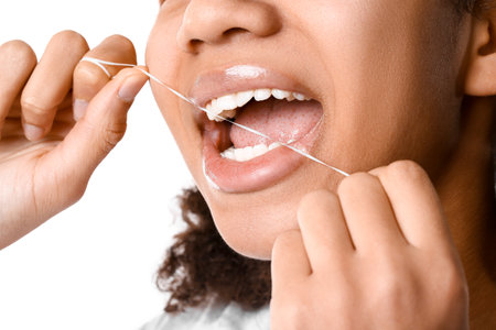 African-American teenage girl flossing teeth on white background, closeupの写真素材