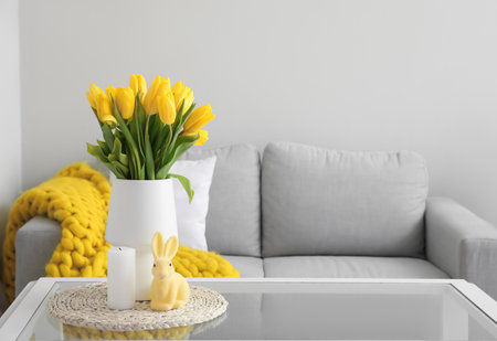 Vase with tulips, candle and Easter rabbit on table in modern living roomの写真素材
