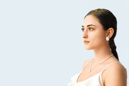 Attractive young woman with unusual shiny makeup on light background