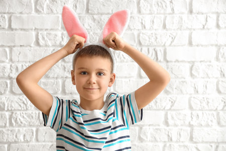 Cute little boy with bunny ears on white brick backgroundの写真素材