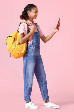 African-American female student with phone on pink background