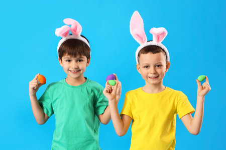 Cute little boys with bunny ears and Easter eggs on blue backgroundの写真素材