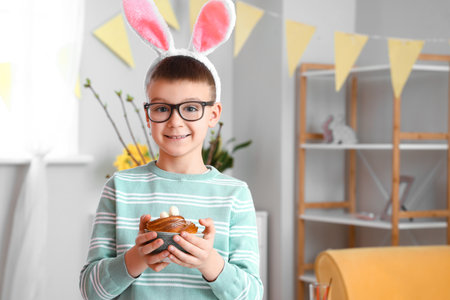 Cute little boy with bunny ears and Easter cake at home
