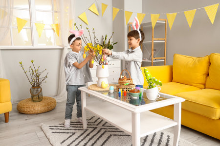 Cute little boys with bunny ears decorating room for Easterの写真素材