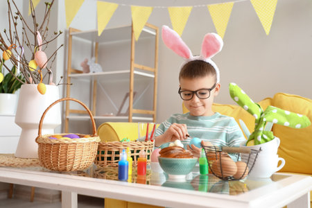 Cute little boy painting Easter eggs at homeの写真素材