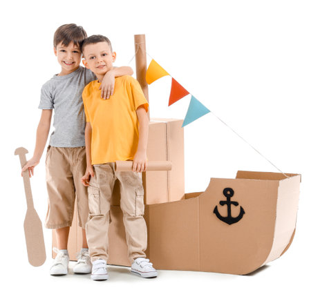 Funny little boys playing with cardboard ship on white backgroundの写真素材