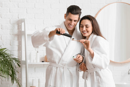 Young couple brushing teeth with activated charcoal tooth paste in bathroomの写真素材