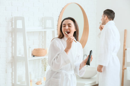 Young couple brushing teeth with activated charcoal tooth paste in bathroomの写真素材