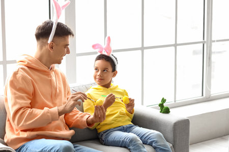 Happy father with his little son painting Easter eggs at homeの写真素材