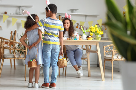 Little children holding baskets with Easter eggs in kitchen, back view