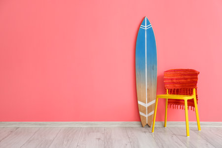 Wooden surfboard and chair with rug near pink wallの写真素材