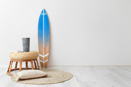 Table with decor, pillow and surfboard near light wallの写真素材