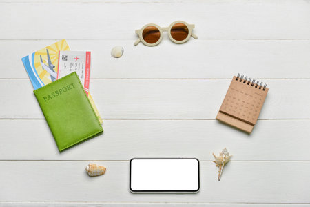 Frame made of passport, mobile phone, calendar and sunglasses on white wooden backgroundの写真素材
