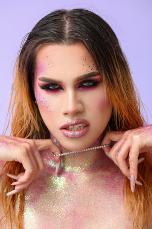 Fashionable young transgender woman with glitters on body against color background