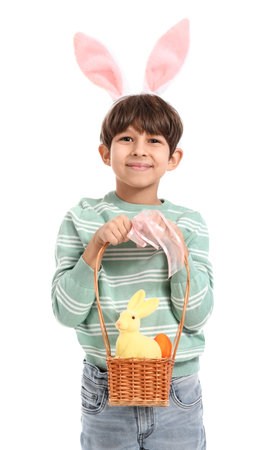 Cute little boy with figurine of bunny and Easter eggs in basket on white background
