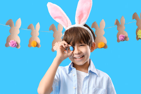 Cute little boy with bunny ears and Easter egg on color backgroundの写真素材